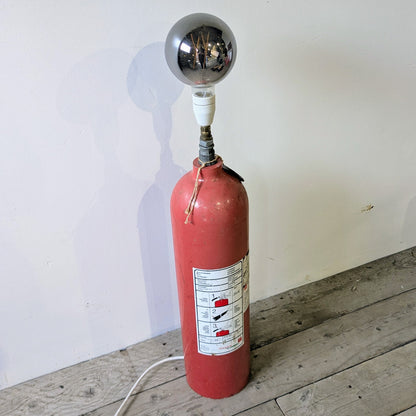 Her ses lampen er lavet af en gammel Falck pulverslukker i metal, som er blevet opcyclet til en gulvlampe.