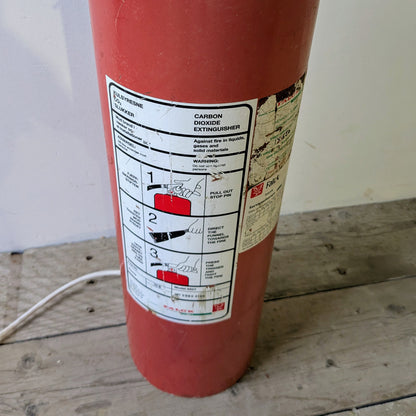 Her ses lampen er lavet af en gammel Falck pulverslukker i metal, som er blevet opcyclet til en gulvlampe.