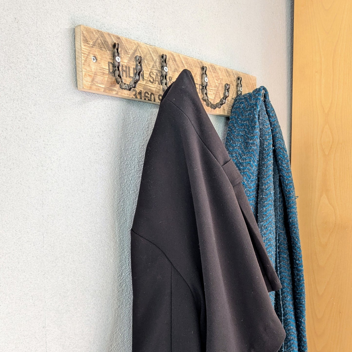 Her ses den rå knagerække med overtøj på, så man kan se den i brug. Knagerækken er produceret af genbrugstræ og genbrugte cykelkæder